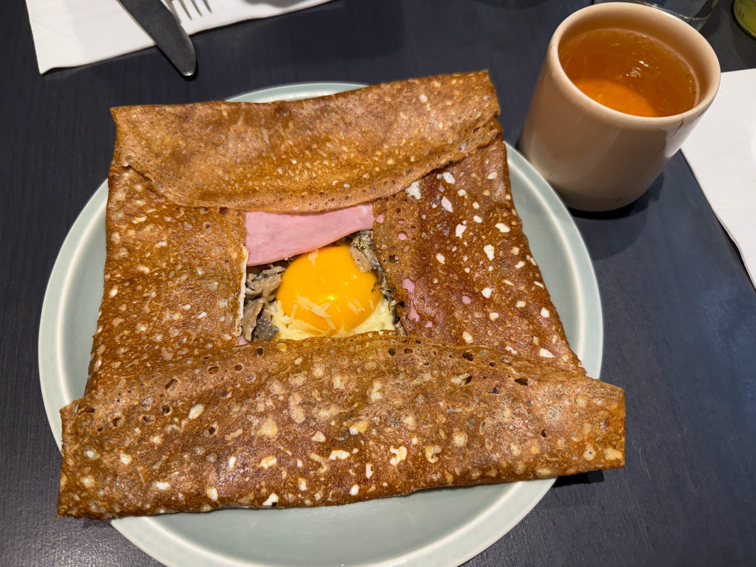 Traditional Crepe Galette made from buckwheat flour with egg, cheese and ham on a plate Brittany, France