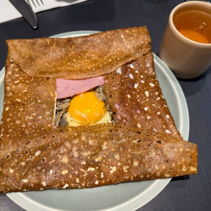 Traditional Crepe Galette made from buckwheat flour with egg, cheese and ham on a plate Brittany, France